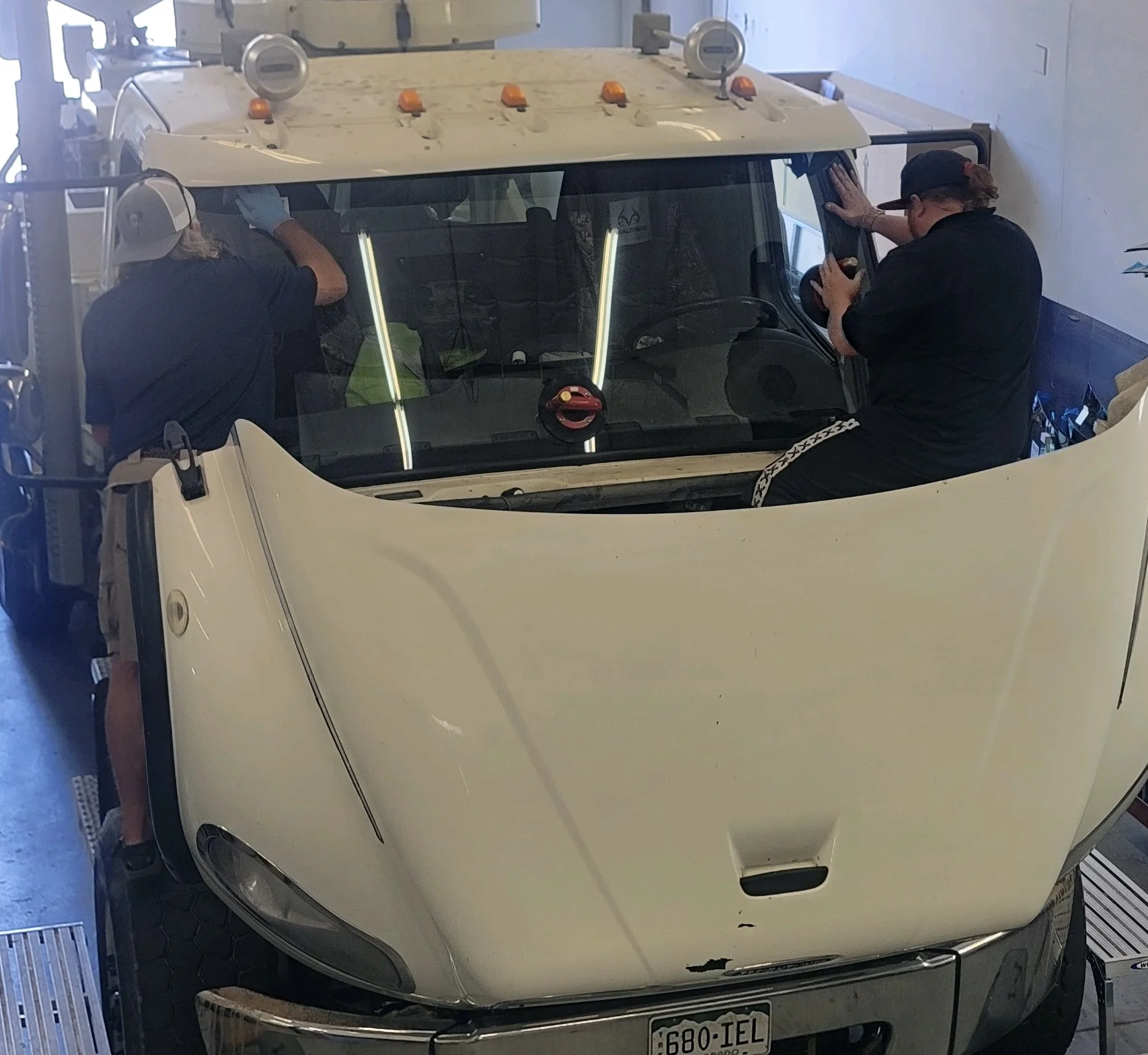 Technicians installing a windshield on a work truck